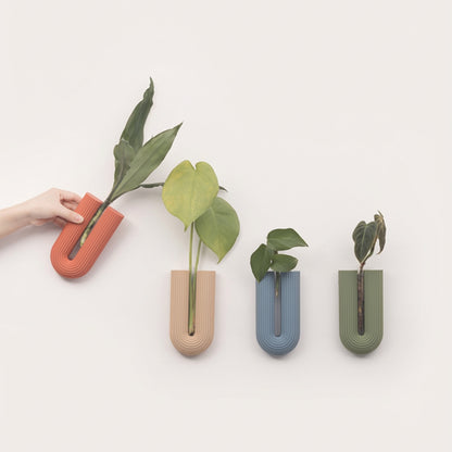 Set of four colorful wall planters with plants on a light background