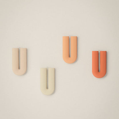 Four letter 'U' shaped objects in different colors on a beige background